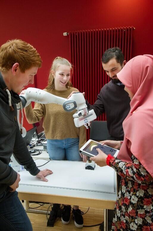 Personen stehen um einen Roboterarm herum