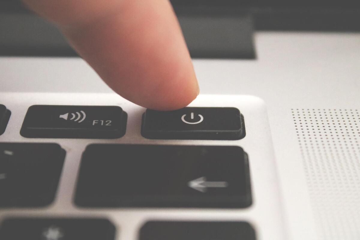 Finger on the power off button on the laptop